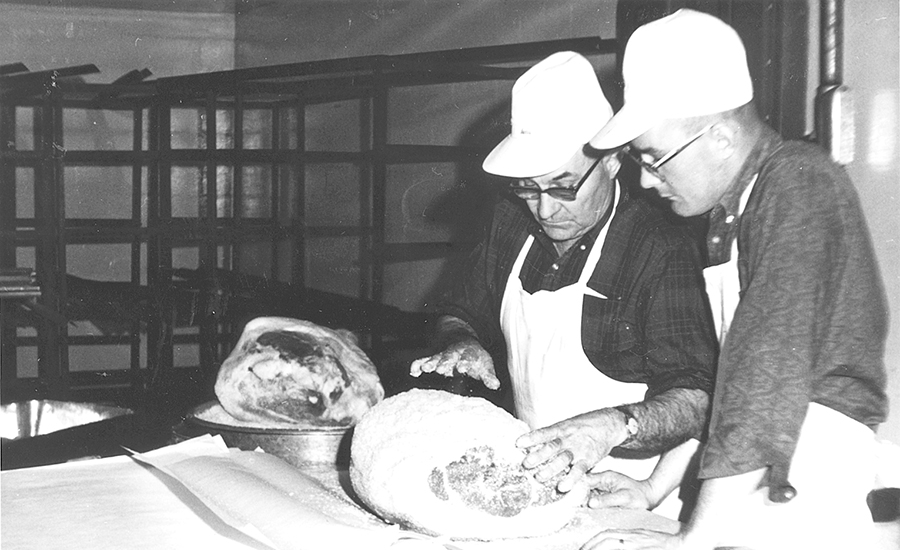 Burgers' founder E.M. Burger showing his son, Morris, how to dry rub a country ham.