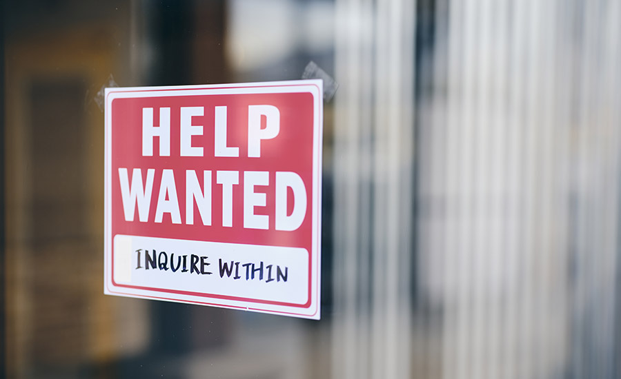 A small business help wanted sign in a window.