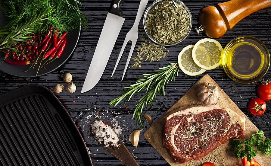 Top view of a kitchen table with a wooden cutting board with beef steak fillet ready for cooking.