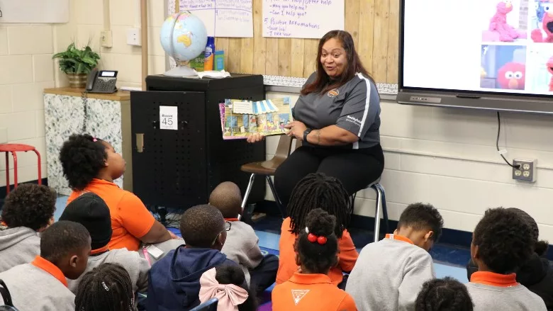 Students listen to Smithfield Foods talent development training specialist reading a book