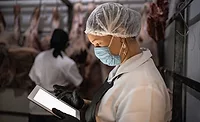 Female butcher using digital tablet with face mask at cold storage Female butcher using digital tablet with face mask at cold storage