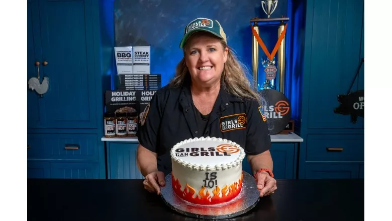 Christie Vanover holds a cake while she celebrates the Girls Can Grill 10-year anniversary