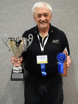 Louis Muench of Louie's Finer Meats holds his Clarence Knebel Memorial Award for Best of Show and Cured Meats Excellence Award.