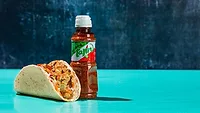 Moe’s Queso Crunch Taco, featuring Tequila Lime Chicken and topped with Tajín Chile Lime seasoning.