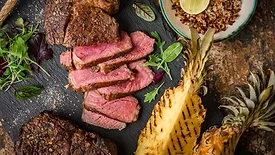 Medium-rare sliced grilled steak served with charred pineapple