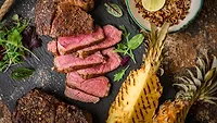 Medium-rare sliced grilled steak served with charred pineapple Medium-rare sliced grilled steak served with charred pineapple