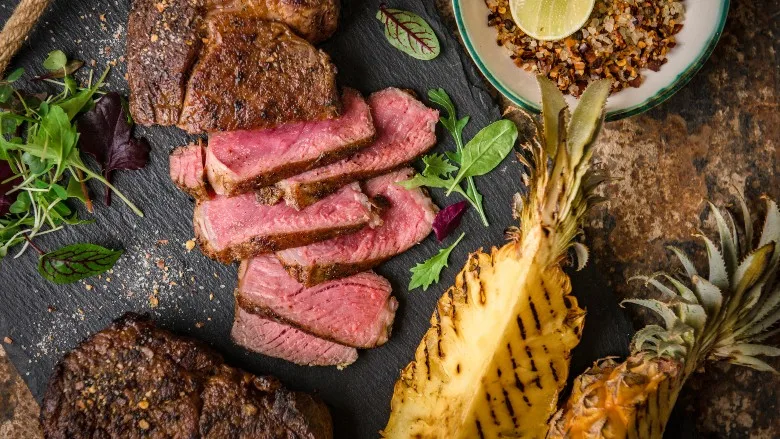 Medium-rare sliced grilled steak served with charred pineapple