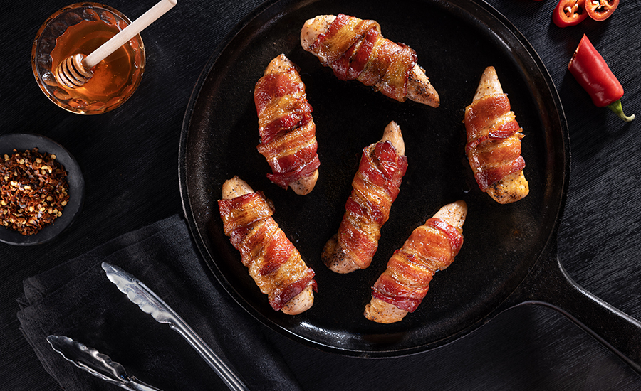 Smithfield Mike's Hot Honey Bacon wrapped on sausages on a plate.
