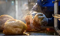 hand cutting a rotisserie chicken
