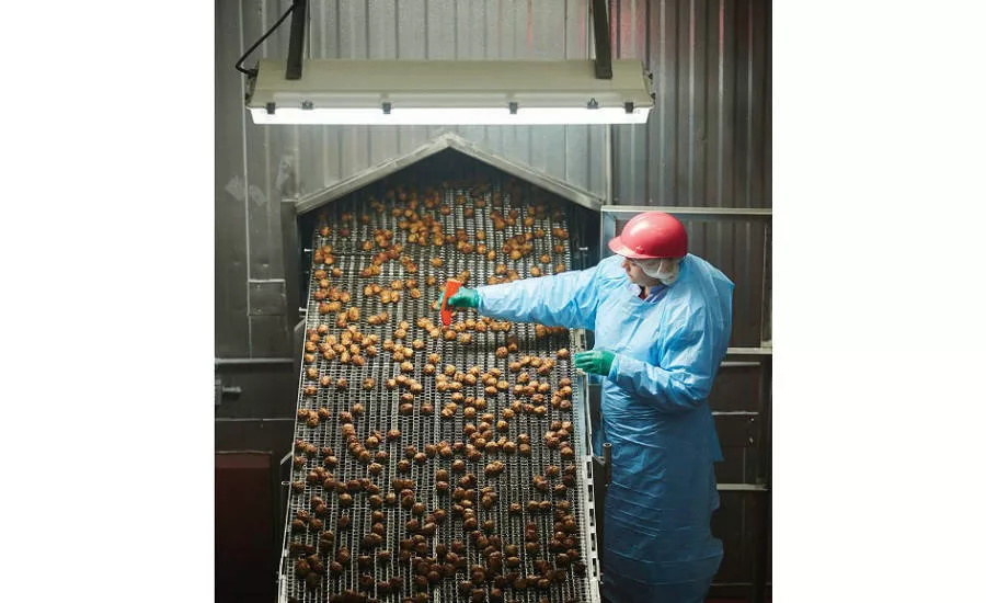 A SugarCreek employee checks fully cooked meatballs on one of the cook lines