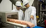 Andy Hanacek and Frank Koekkoek Jr., complex manager for Raeford, talk about the startup of the ground turkey tray-pack line running during Hanacekâs visit to the new facility in mid-November