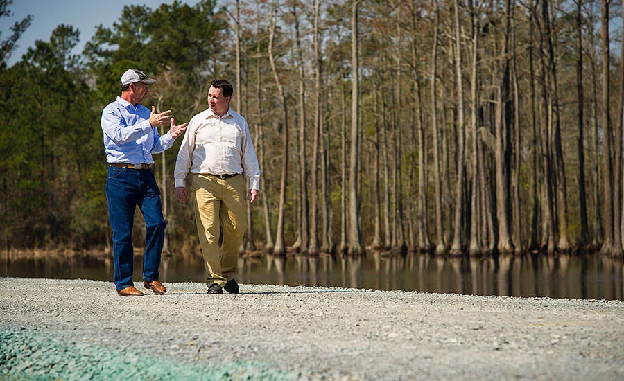 Pic Billingsley and Andy Hanacek walk along an earthen dam at Sanderson Farms’ St. Pauls, N.C., plant