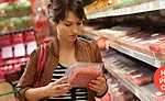 Woman Reading Ingredients on Food Label for Meat Product
