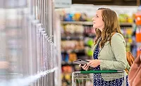 Woman Looking at Frozen Food in Grocery Aisle Woman Looking at Frozen Food in Grocery Aisle