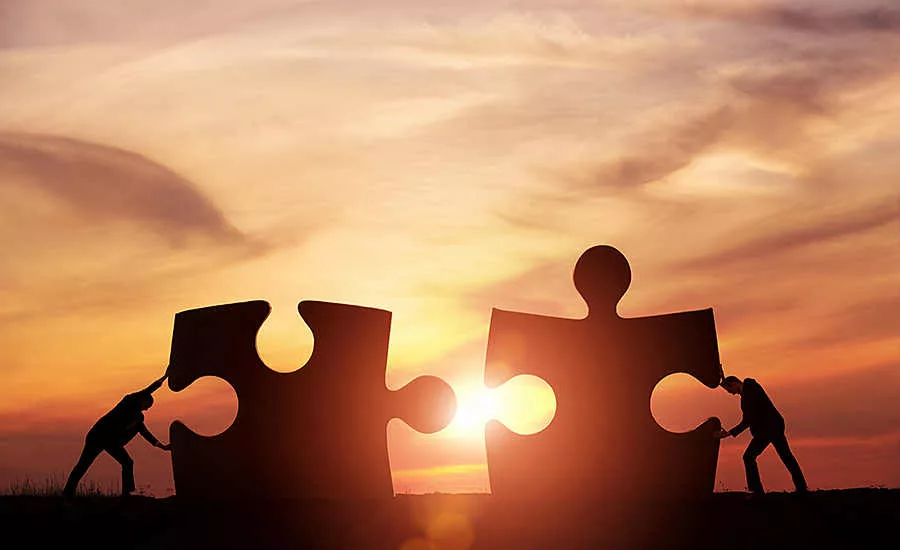 Two People Pushing Puzzle Pieces Together
