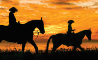 Silhouette of Adult and Child Horseback Riding at Sunset