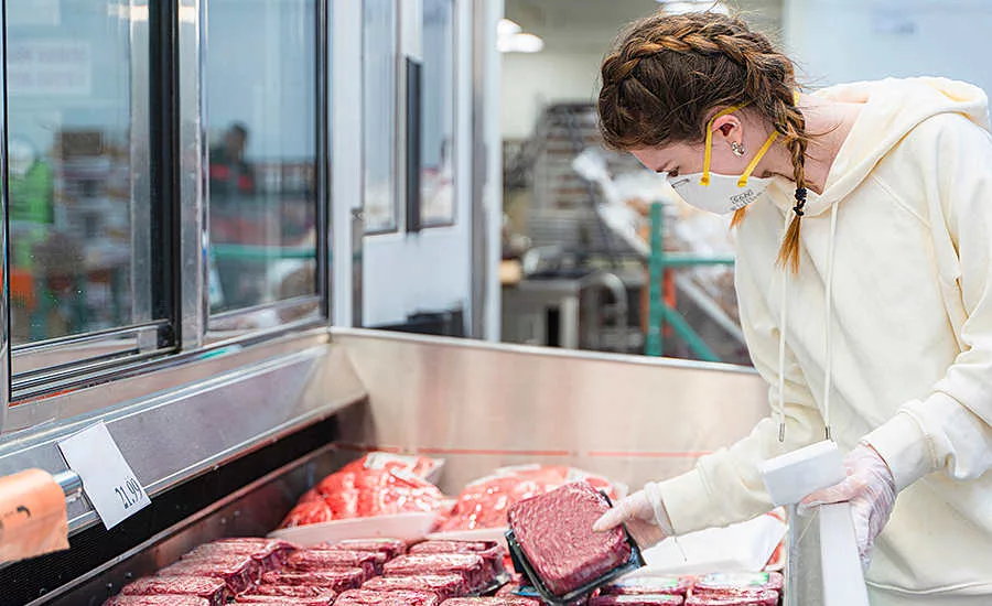 girl in a mask shopping for meat