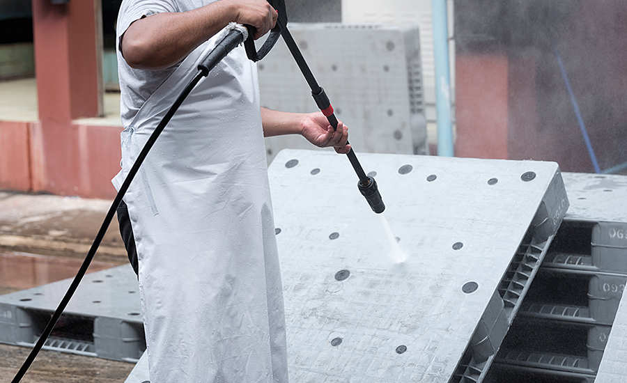 worker spraying kitchen equipment clean