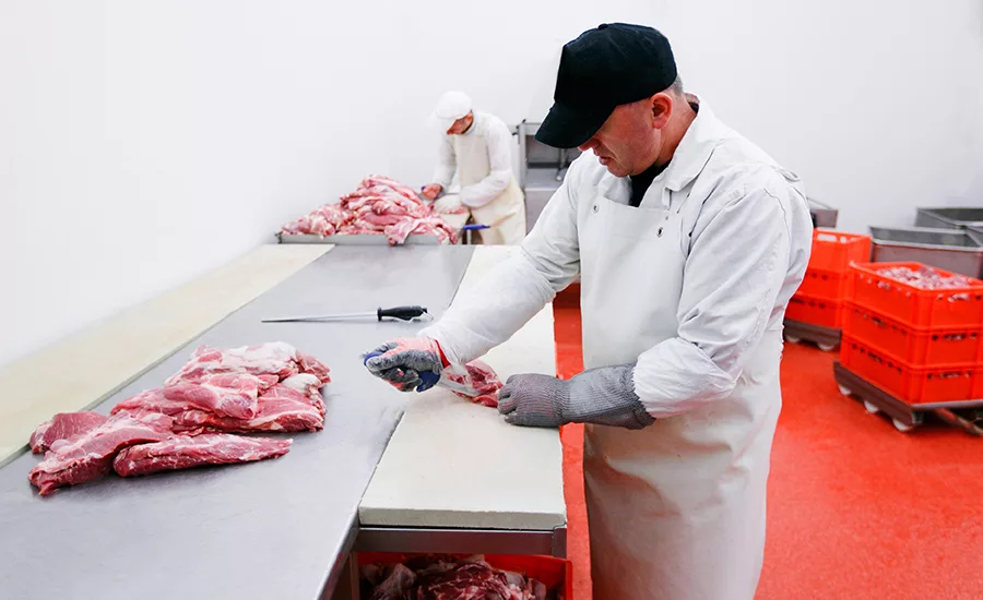 Butcher cutting meat on a counter.