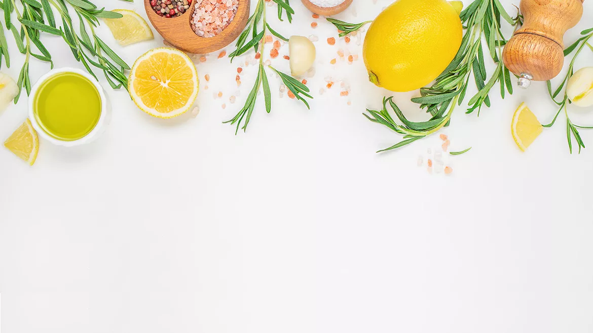 Lemons, rosemary, sea salt, garlic cloves, and olive oil at the top on a white background.