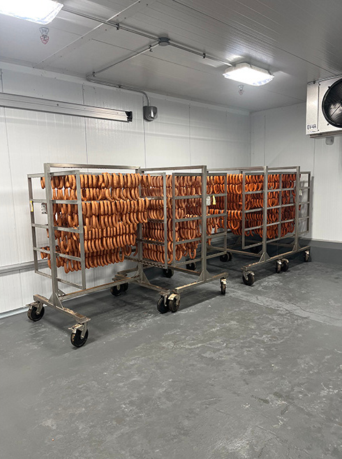Sausages hanging on a rack in a food processing facility.