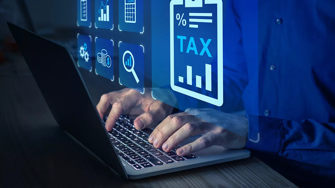 Man typing on a laptop as virtual financial icons float over his hands.