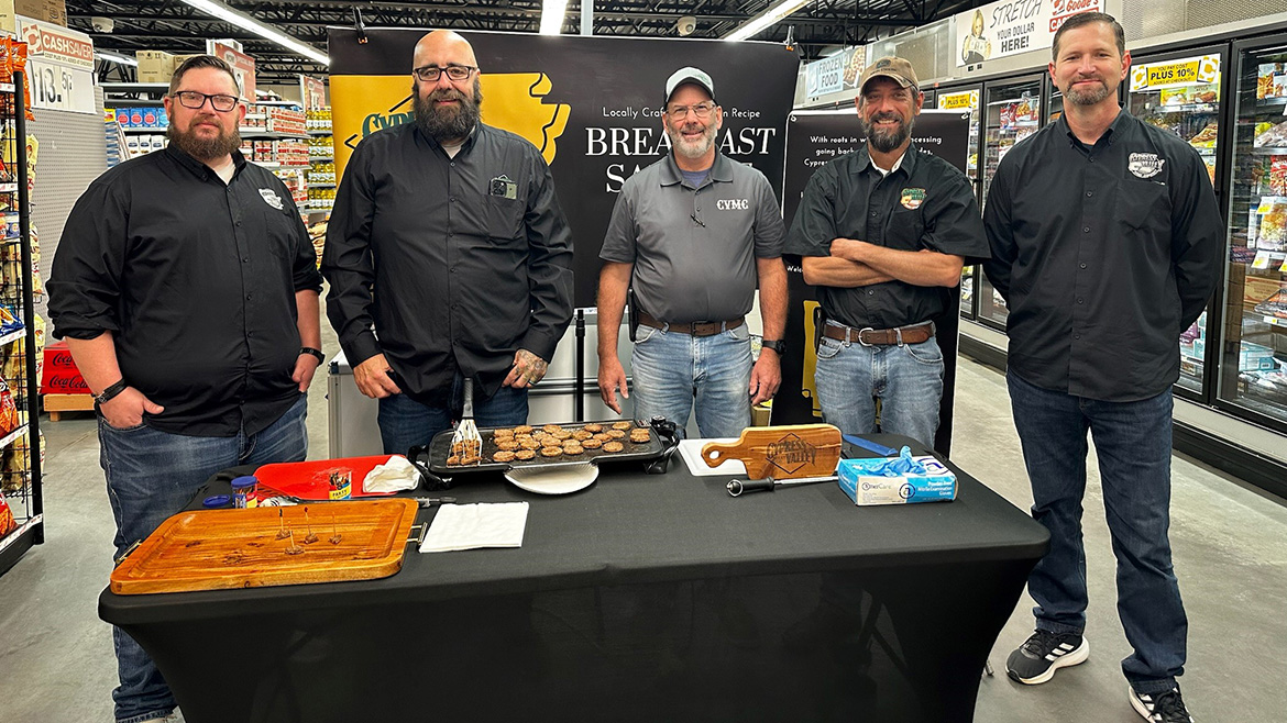 A group of employee owners posing in front of a display in a grocery store.