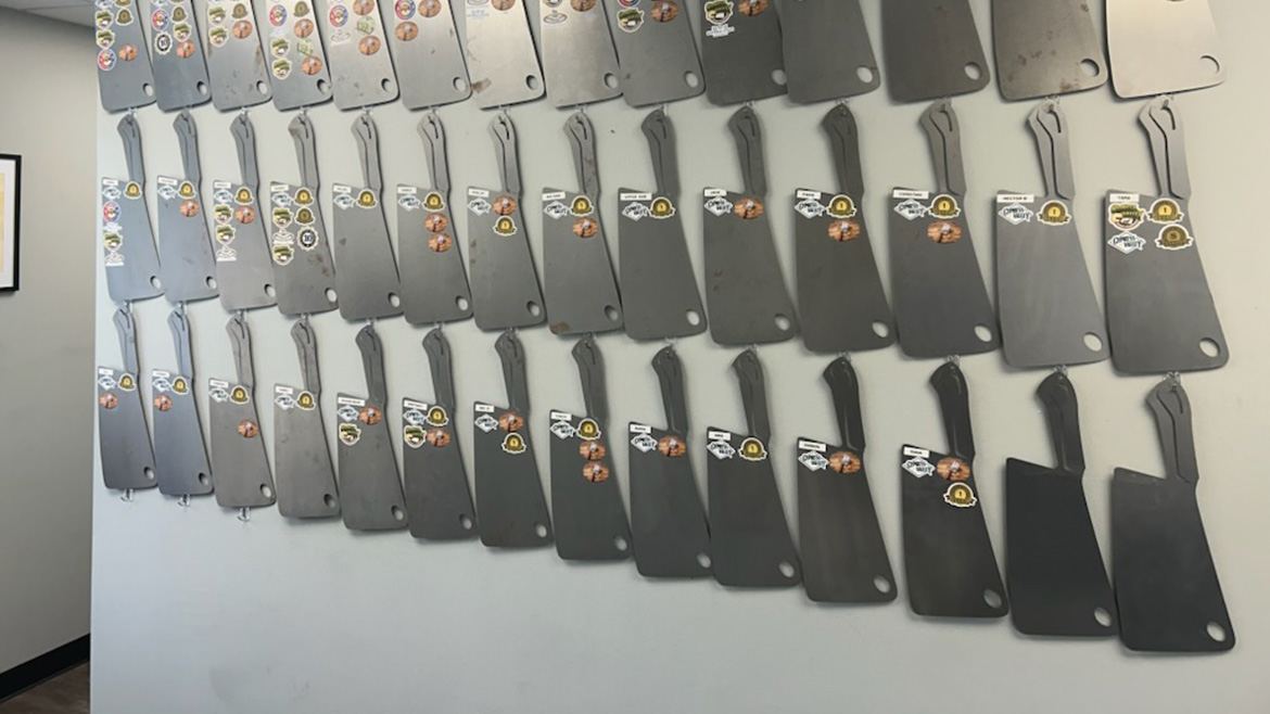 The Employee Ownership Trust wall of meat cleavers with stickers on each.