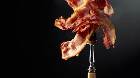 Cooked bacon on a fork.