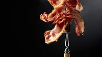 Cooked bacon on a fork Cooked bacon on a fork.
