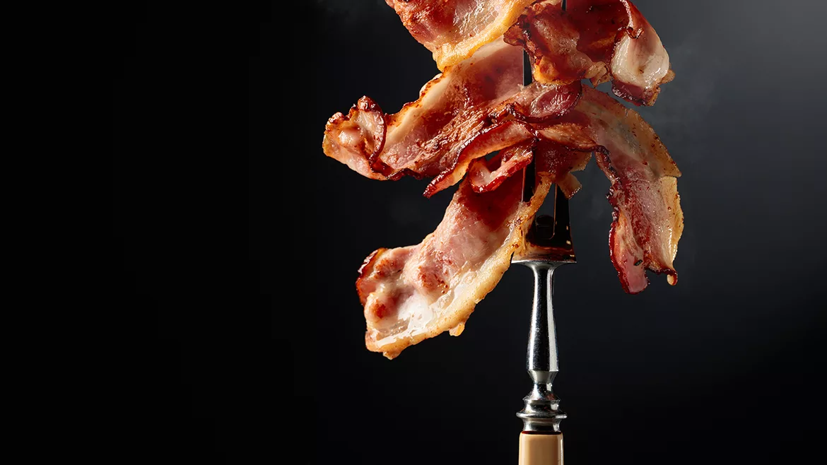Cooked bacon on a fork.