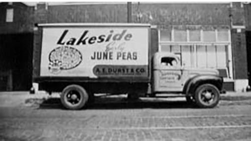 Black and white photo of a vintage delivery truck for Lakeside Early June Peas, parked on a street.