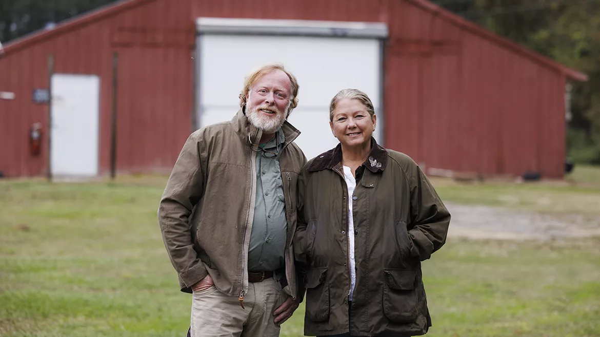 Matt Miller, Manchester Farms’ purchasing director, and Brittney Miller, owner of Manchester Farms posing outside, a red barn is in the background.