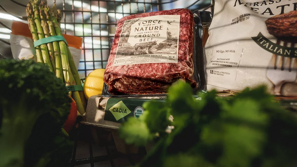 A close-up image of Force of Nature 100% ground beef in a grocery cart with other groceries.