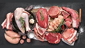 Several cuts of beef, pork and chicken on a wooden board, cast iron pan and salt.