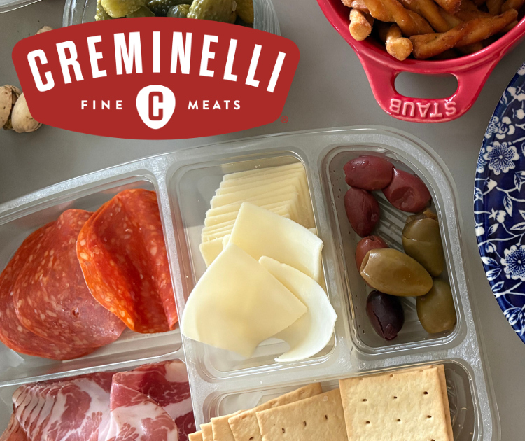 Creminelli Entertaining tray of meats, cheese, crackers and olives next to a plate and other snack.