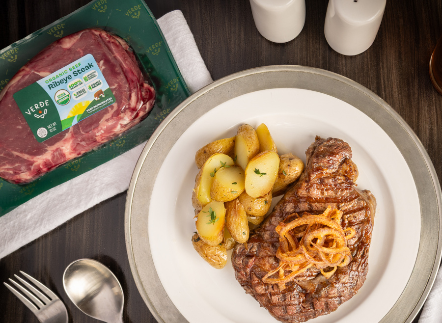 A package of Verde Farms Ribeye Steak and cooked steak on a plate.