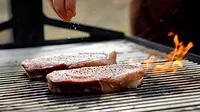 two thick steaks grilling over an open flame two thick steaks grilling over an open flame