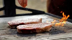 two thick steaks grilling over an open flame two thick steaks grilling over an open flame