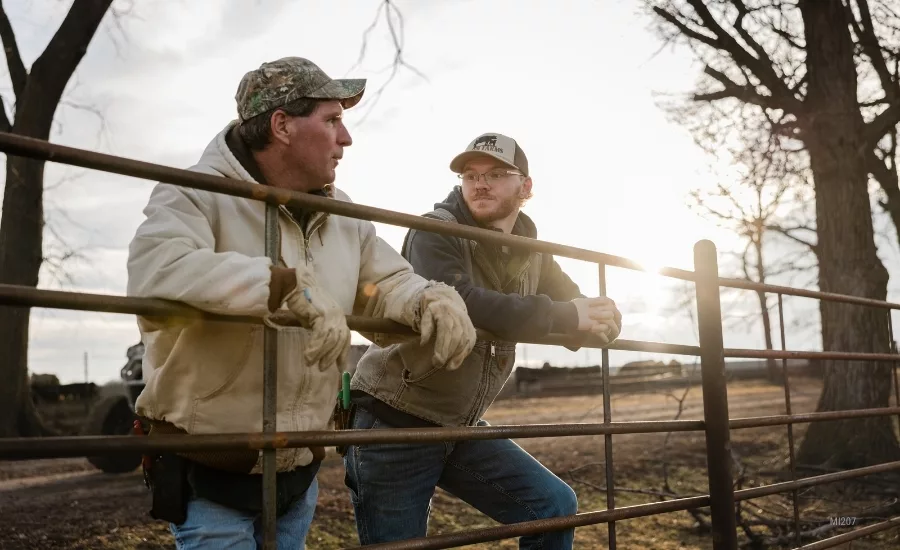  two individuals standing by a farm gate