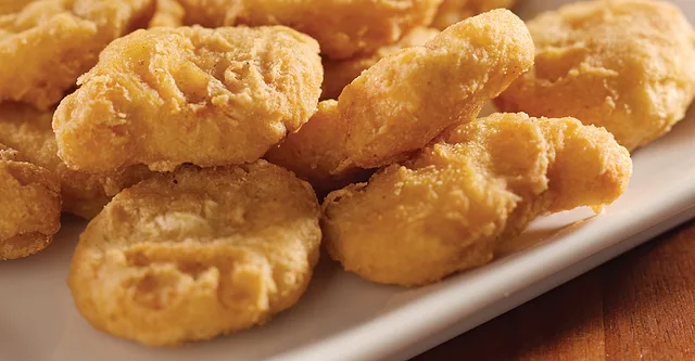 Breaded chicken nuggets on a white plate.
