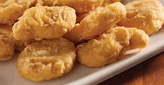 Breaded chicken nuggets on a white plate.