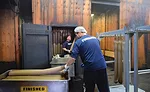 A Worker Places Lebanon Bologna Logs in a Cart After They Come Out of the Smokehouse