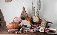 Display of various deli meats on a table and hanging.