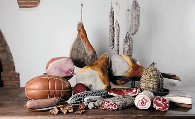 Display of various deli meats on a table and hanging.