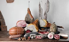 Display of various deli meats on a table and hanging.