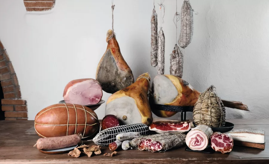 Display of various deli meats on a table and hanging.